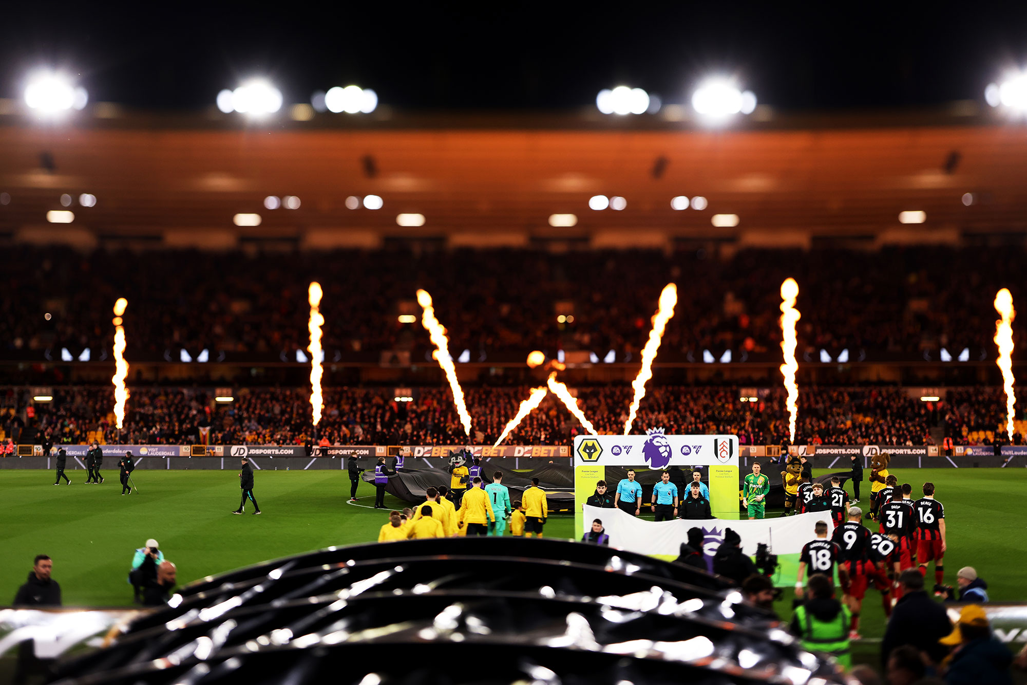 Premier League stadium player walkout with pyrotechnics and stewards pitchside — major event security environment